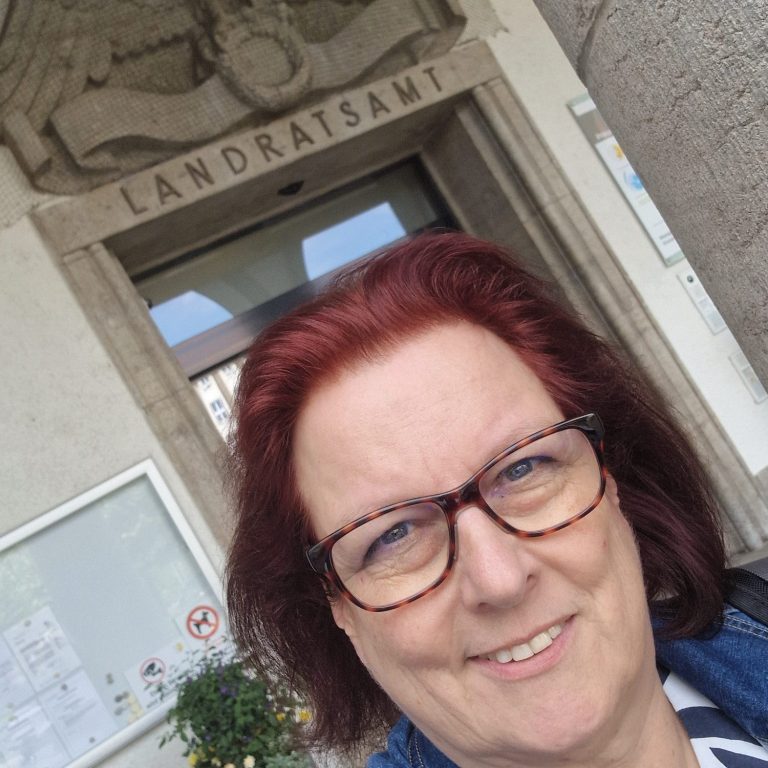 Landratsamt Augsburg Claudia Schuster lächelt vor dem Landratsamt-Eingang.